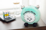 Mint green plush alarm clock with cute face saying You Snooze You Lose on desk