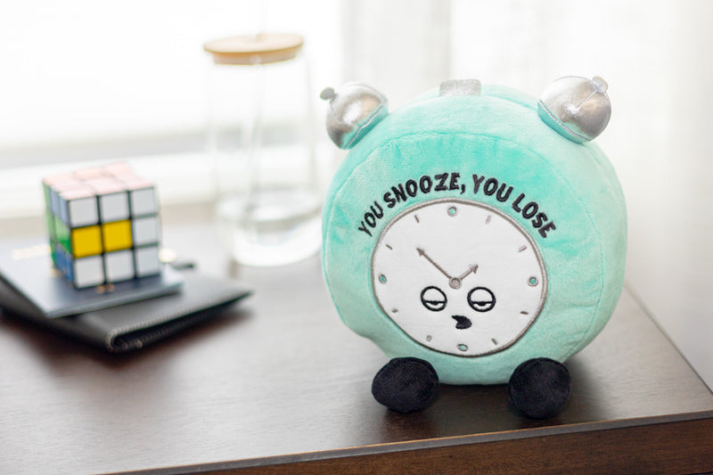 Mint green plush alarm clock with cute face saying You Snooze You Lose on desk