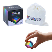 A 3D optical illusion cube puzzle shown with its black branded box, a white drawstring bag, and a hand holding the small multicolored cube against a light gray background.