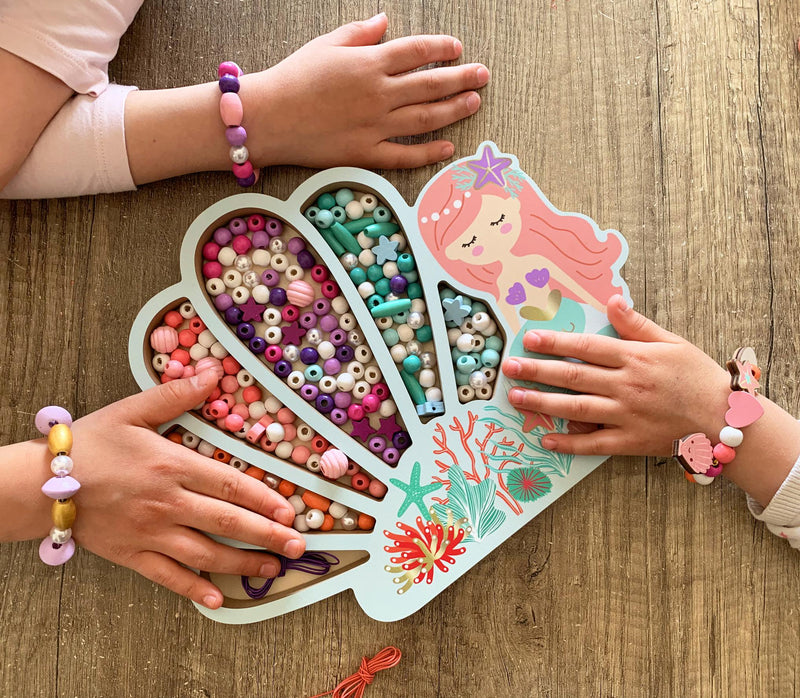 Children making jewelry with mermaid-themed wooden beads in heart-shaped organizer tray