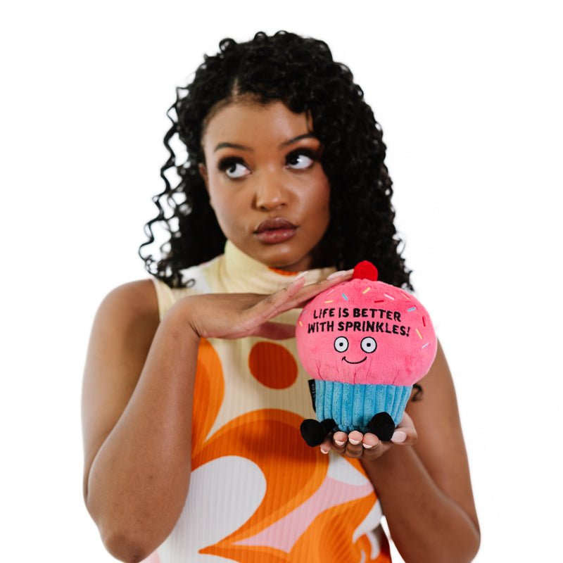 Model holding pink plush cupcake with 'Life Is Better With Sprinkles' text