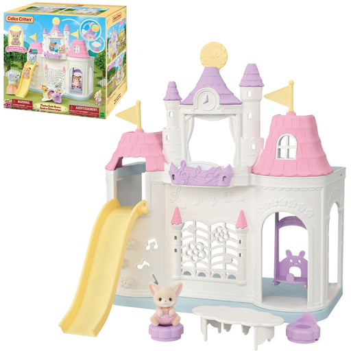 A Calico Critter toy castle playset shown with its retail box in the upper left. The castle is primarily white with pink roofs, lavender-purple towers and accents, a yellow slide, and a small calico cat figure standing in front.