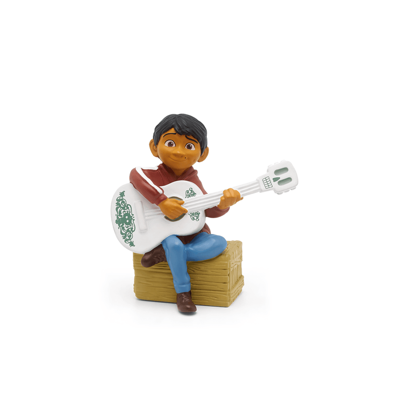 Tonie figurine of Miguel from Disney Coco holding white guitar sitting on wooden crate