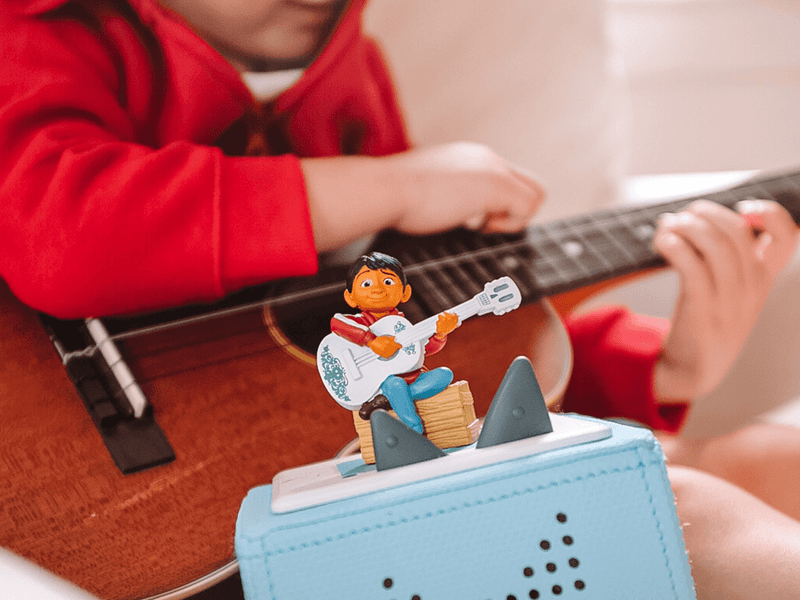 Disney Coco Tonie figurine on Toniebox with child playing guitar in background