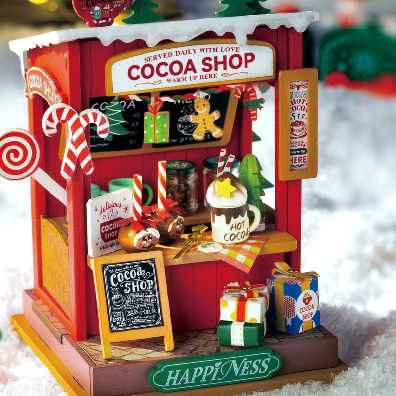 Miniature cocoa shop model with festive decorations on a snowy background