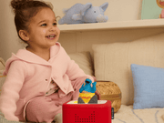 Child playing with blue Cookie Monster Tonie on red Toniebox speaker in bedroom