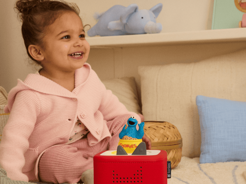 Child playing with blue Cookie Monster Tonie on red Toniebox speaker in bedroom