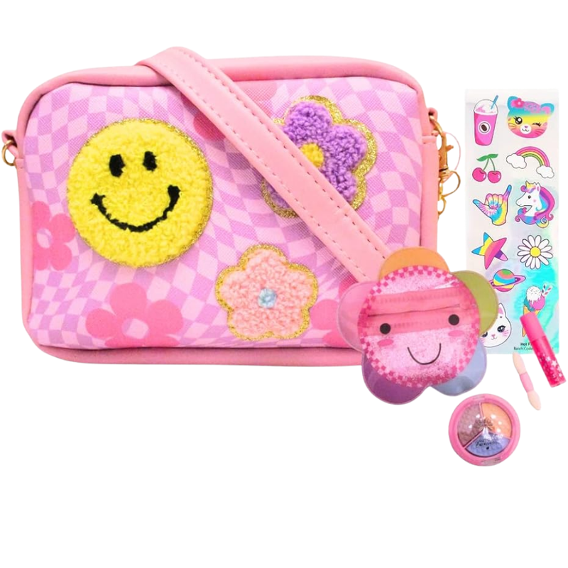 Pink crossbody bag from Hot Focus with smiley face patch and decorative accessories on white background.