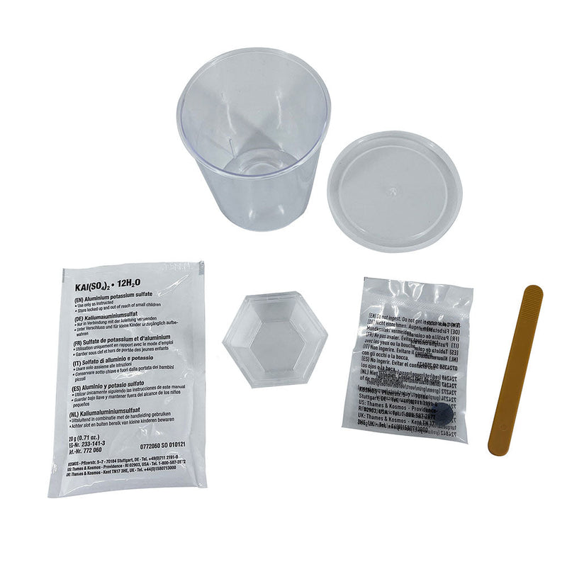 Crystal growing kit contents including plastic containers, chemical packets, and stirring stick