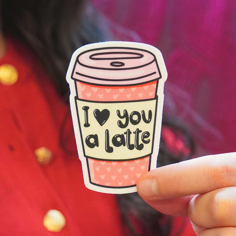 Hand holding pink vinyl sticker with coffee cup design saying I love you a latte