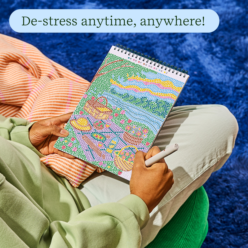 Person relaxing outdoors doing FlowArt dot-by-letter cozy cottage puzzle with colorful dotted scene