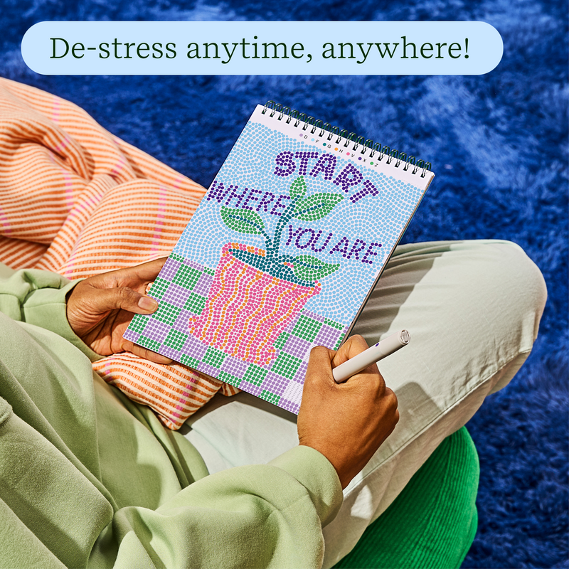 Person using FlowArt dot-by-letter activity book with colorful cactus design while relaxing outdoors