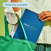 Person holding blue Lifelines FlowArt dot-by-letter notebook from green tote bag