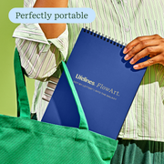 Person holding blue Lifelines FlowArt dot-by-letter notebook in green tote bag