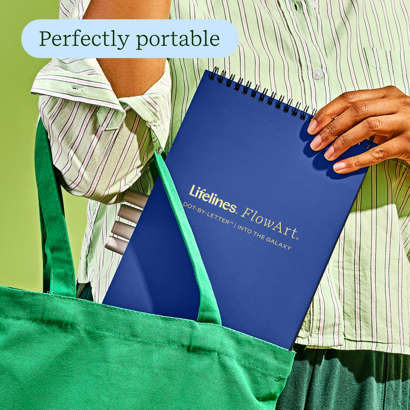 Person holding blue Lifelines FlowArt dot-by-letter notebook in green tote bag
