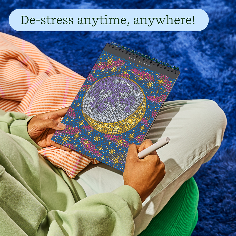 Person relaxing while working on FlowArt dot-by-letter galaxy-themed art pad with colorful dotted design