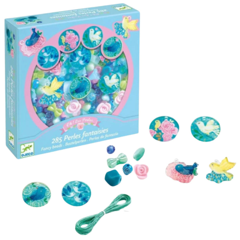 A children's bead craft kit box in light blue with pink trim, shown with scattered beads, buttons, bows, flowers, and bird motifs on a white background. The packaging reads '285 Perles fantastiques' and shows the Daka brand logo.