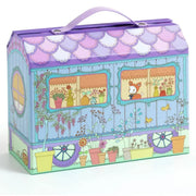 A decorative purple and pastel blue playset box with a handle, featuring a whimsical garden and house illustration on the front.