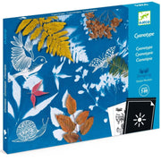 Box featuring a Cyanotype Starter Kit of a bird, butterfly, snail, leaves, and berries on a blue background, with a small inset showing the black-and-white puzzle sheet.