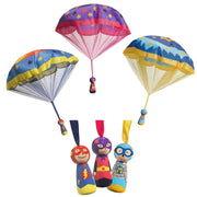 Three colorful parachute toys with matching plush superhero characters below each parachute, shown on a plain white background.