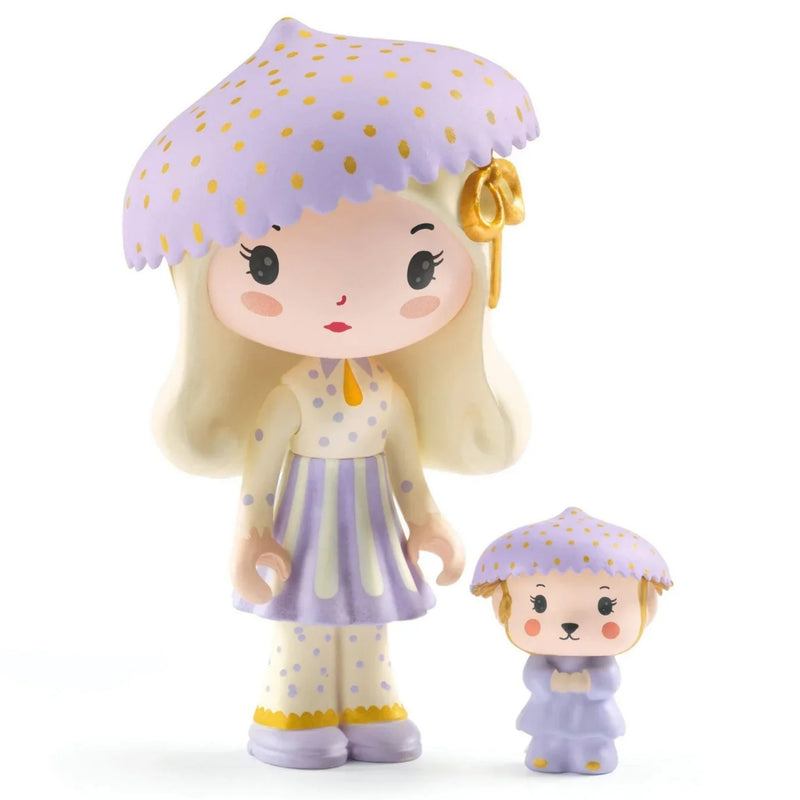 Two stylized doll figures on a plain white background: a larger figure with long blonde hair, a lavender umbrella with gold dots, a cream dress with lavender stripes, and a small matching figure beside it.