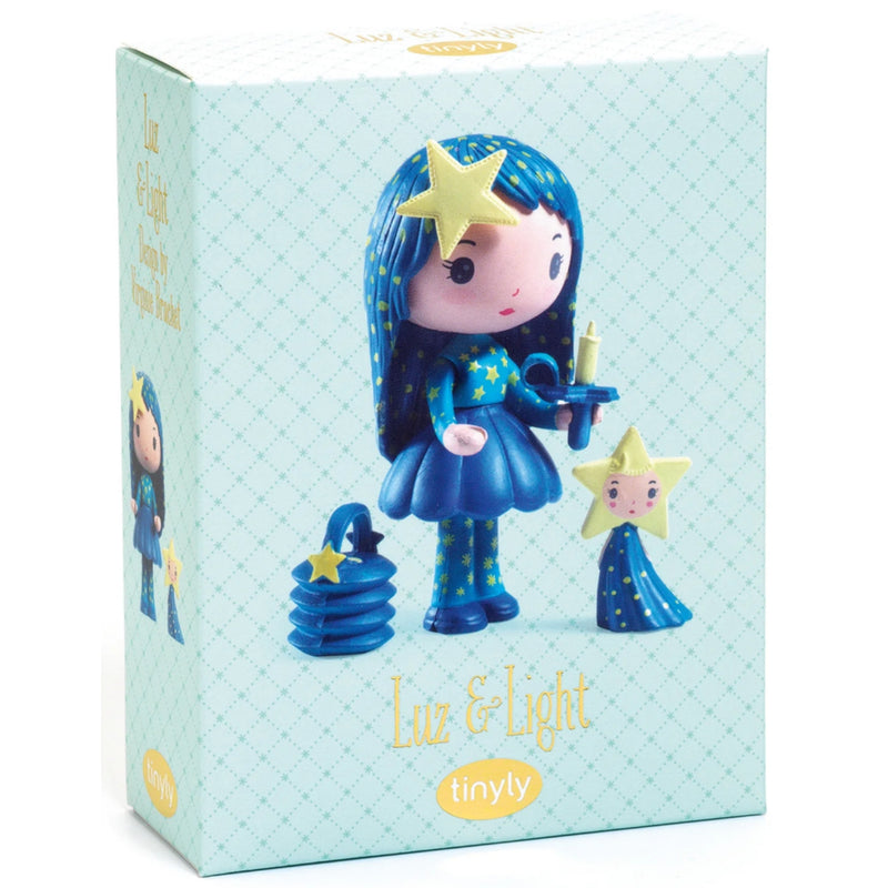 The product packaging box for the 'Luz & Light' star fairy figurine by Tinyly. The box is light blue with a subtle diamond pattern, featuring an illustration of the blue-haired star girl in a star dress holding a candle, with a smaller star version of herself beside her.