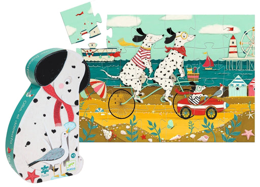 A children's jigsaw puzzle and its matching rounded rectangular box shown on a white background. The artwork features two Dalmatian dogs riding bicycles on a seaside pier with boats, buildings, and a lighthouse.