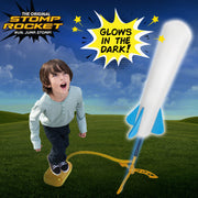 Child launching a glowing JR Glow rocket at dusk with the kid-powered stomp launcher.
