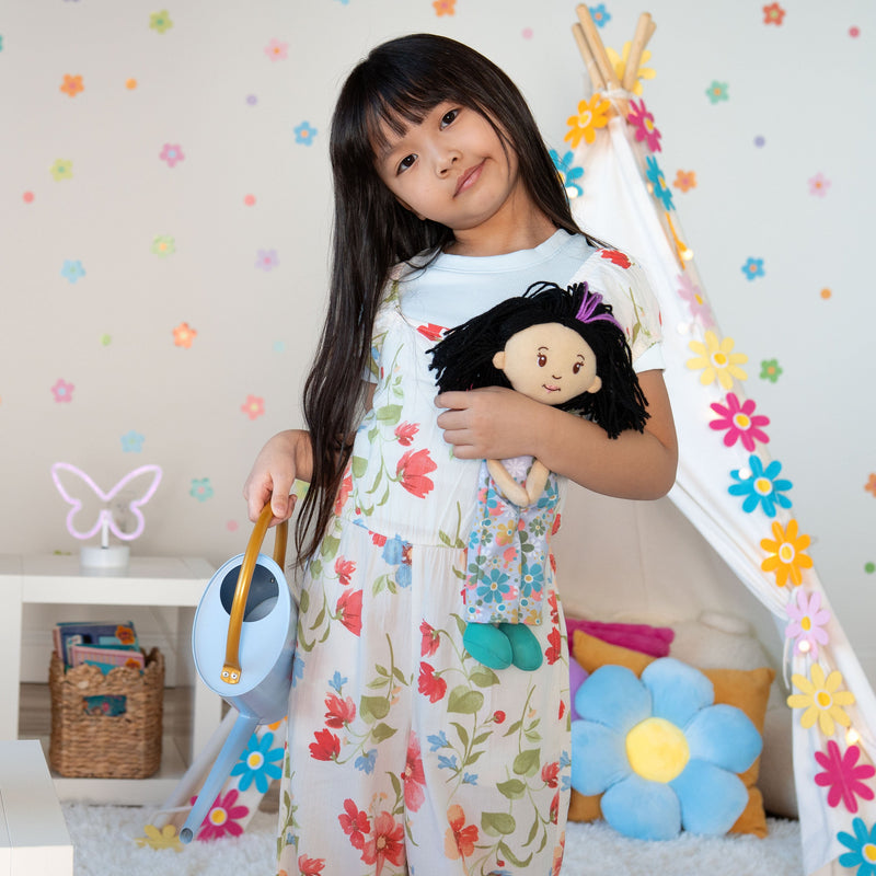 Young girl holding Groovy Girls Daisy doll with black hair in colorful playroom setting