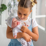 Young girl holding a baby doll in a bright indoor setting