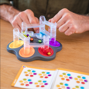 Person playing with the Drop Zone game on a wooden table.