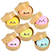 Set of colorful round dumplings with faces in open beige containers on a white background