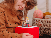 Child playing with Tonie Eloise figure on red Toniebox speaker