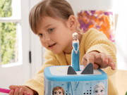 Child playing with Tonie Disney Frozen figure on blue Toniebox speaker device
