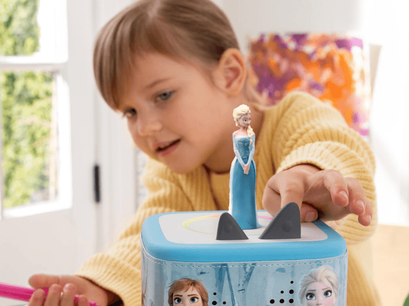 Child playing with Tonie Disney Frozen figure on blue Toniebox speaker device
