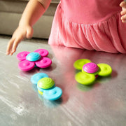 Colorful flower-shaped toys on a reflective surface with a child's hand in the background.