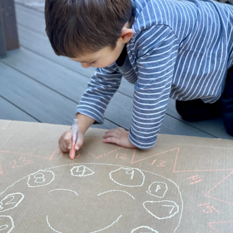 Child drawing with Wonder Stix chalk on concrete surface showing colorful artwork