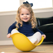 Child sitting on a yellow Bilibo indoors.