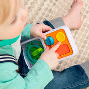 Child playing with PlayTab Go a colorful educational toy on a carpeted floor