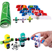 Soccer-themed toy set from Fat Brain including a rolled green field mat, multiple colorful flag-shaped pieces, small soccer player figures, and a hand holding one of the toy figures against a white background.
