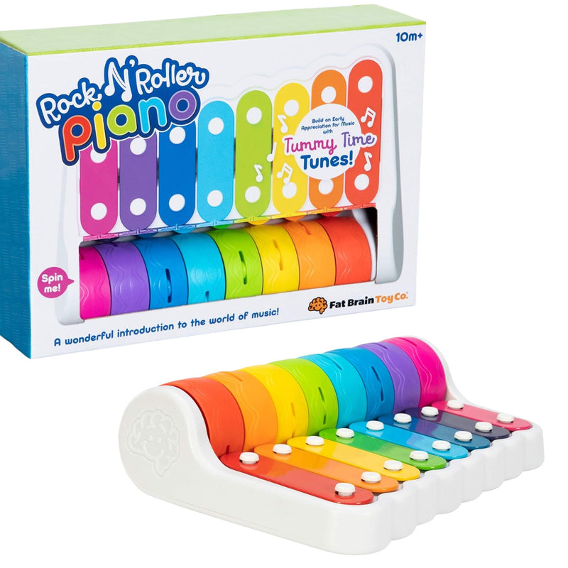 Rock 'N Roller Piano toy and its retail packaging, featuring a rainbow-colored piano with white roller wheels on a clean white background. The packaging displays the brand 'Fat Brain Toy Co.