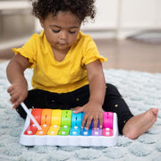 Child playing with a colorful Rock N Roller Piano toy on a carpeted floor.