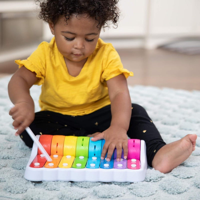 Child playing with a colorful Rock N Roller Piano toy on a carpeted floor.