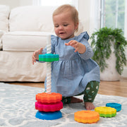 Child playing with SpinAgain's colorful stacking toy on a rug in a living room.