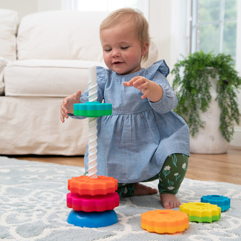 Child playing with SpinAgain's colorful stacking toy on a rug in a living room.