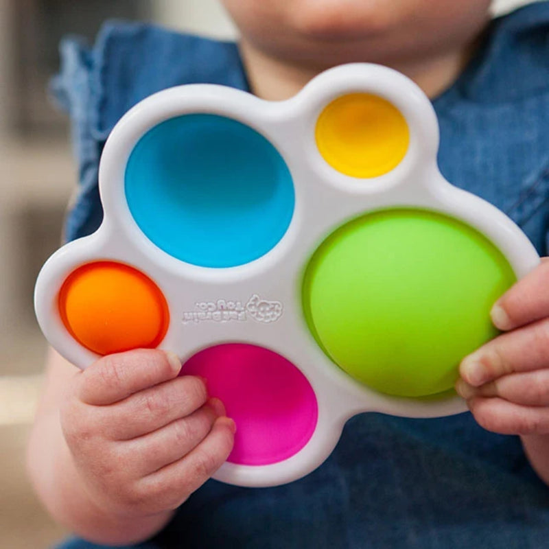 Child holding a colorful fidget toy with blue, yellow, green, orange, and pink dots.