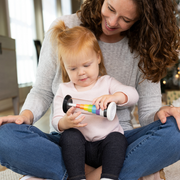 Woman and child playing with the Flipty from Fat Brain Toys which changes from a rainbow coloration to black & white when turning the toy.