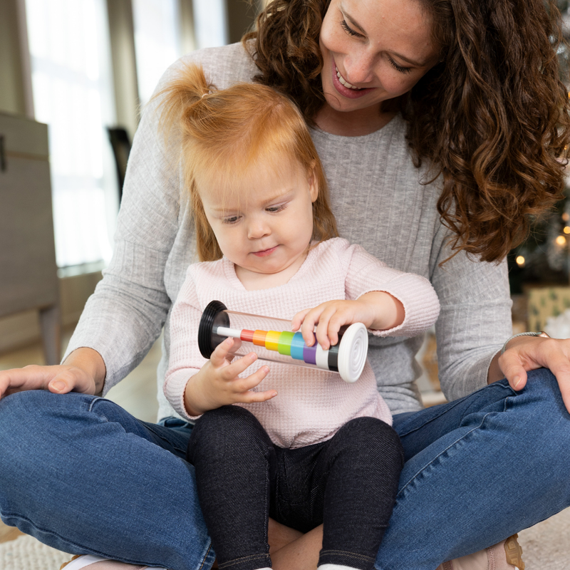 Woman and child playing with the Flipty from Fat Brain Toys which changes from a rainbow coloration to black & white when turning the toy.