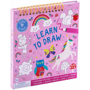 A pink spiral-bound children's drawing book titled 'Learn to Draw' with whimsical illustrations including a unicorn, rainbow, owl, clouds, and butterflies on the cover.