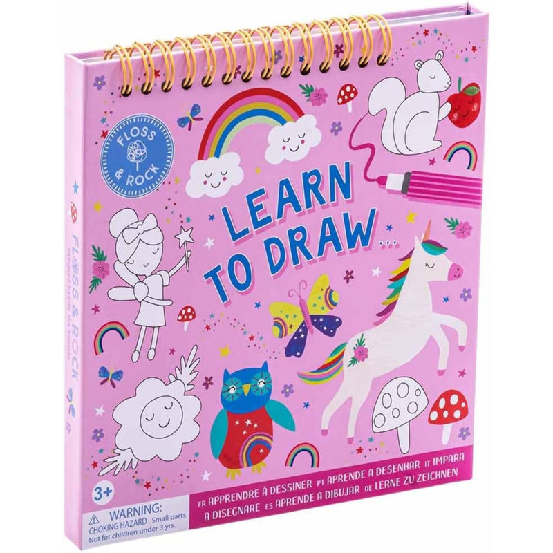 A pink spiral-bound children's drawing book titled 'Learn to Draw' with whimsical illustrations including a unicorn, rainbow, owl, clouds, and butterflies on the cover.